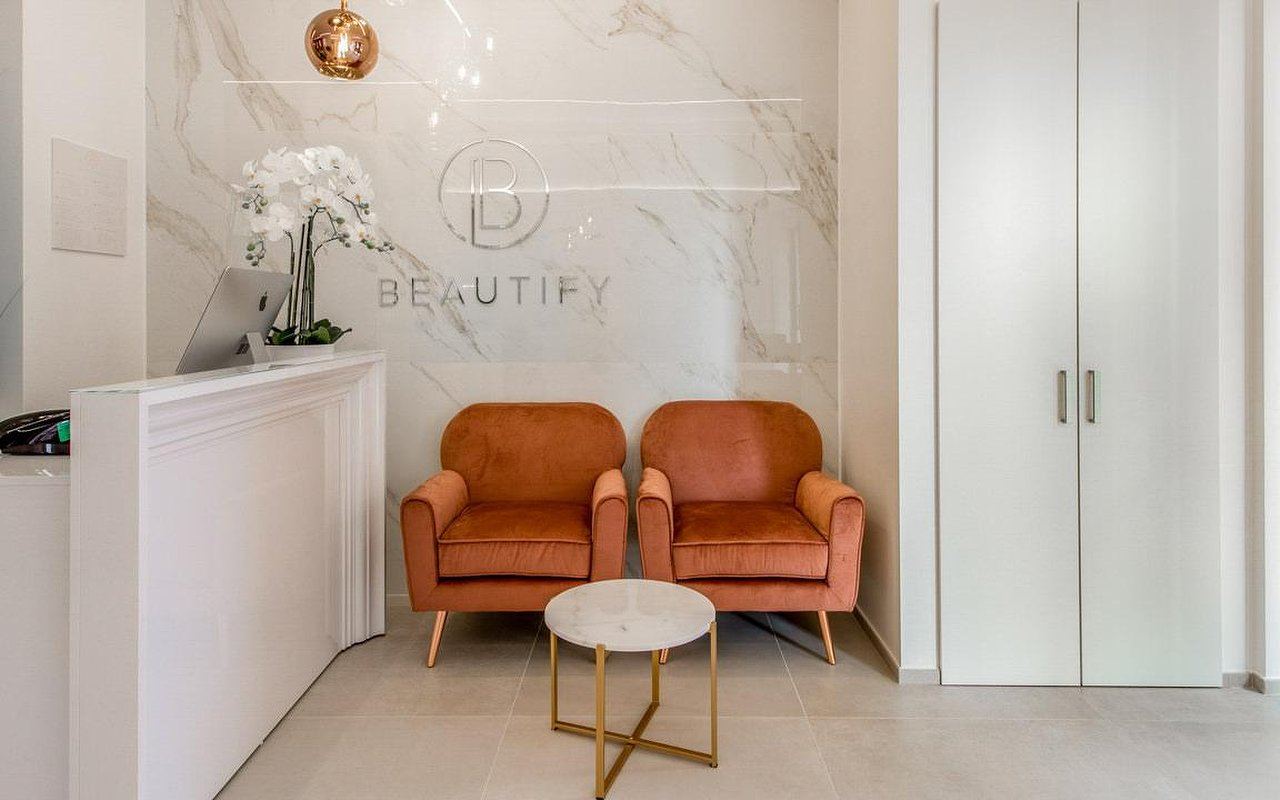 Zona accoglienza con due poltrone in velluto e logo Beautify