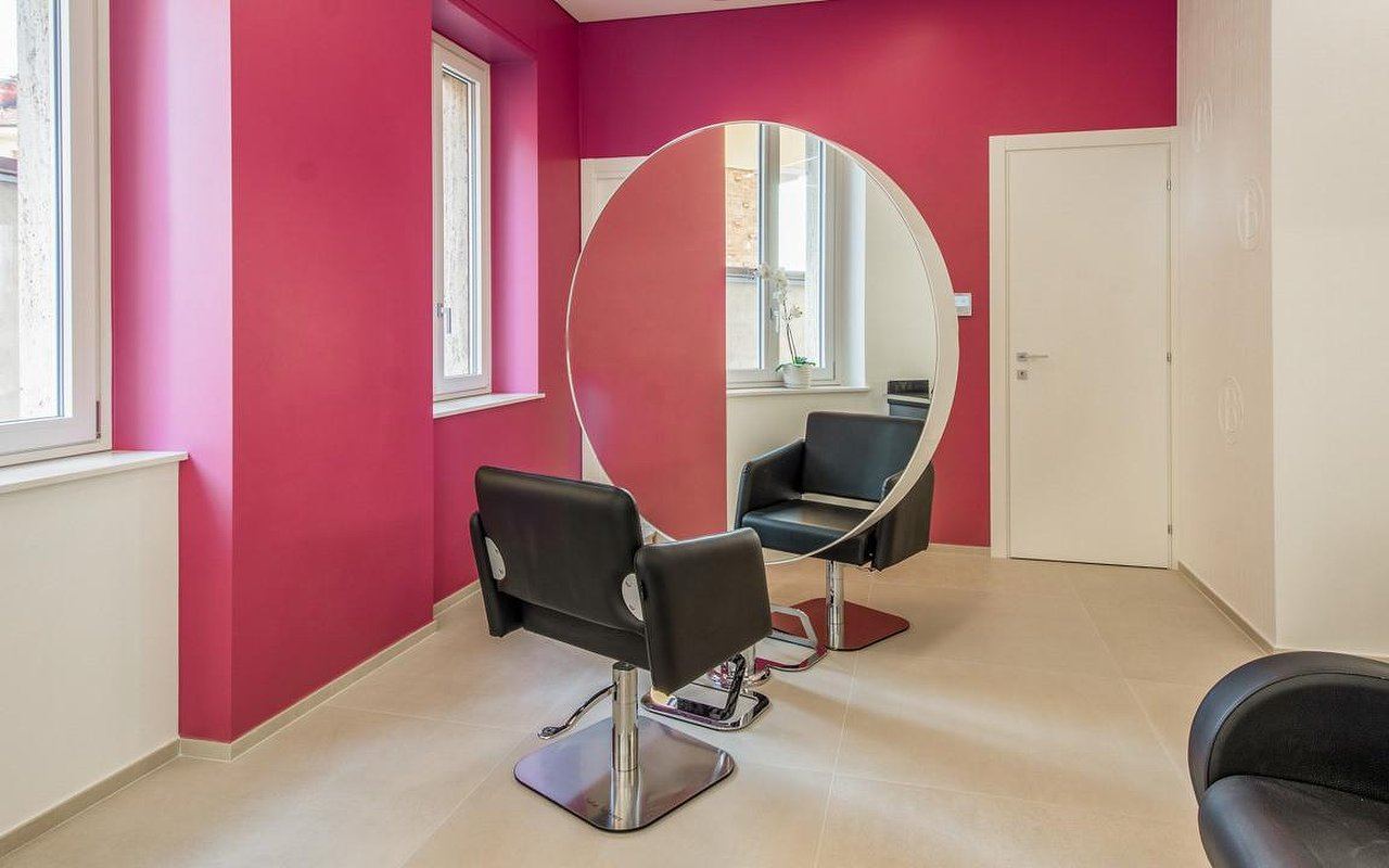 Postazione con grande specchio tondo e parete fucsia