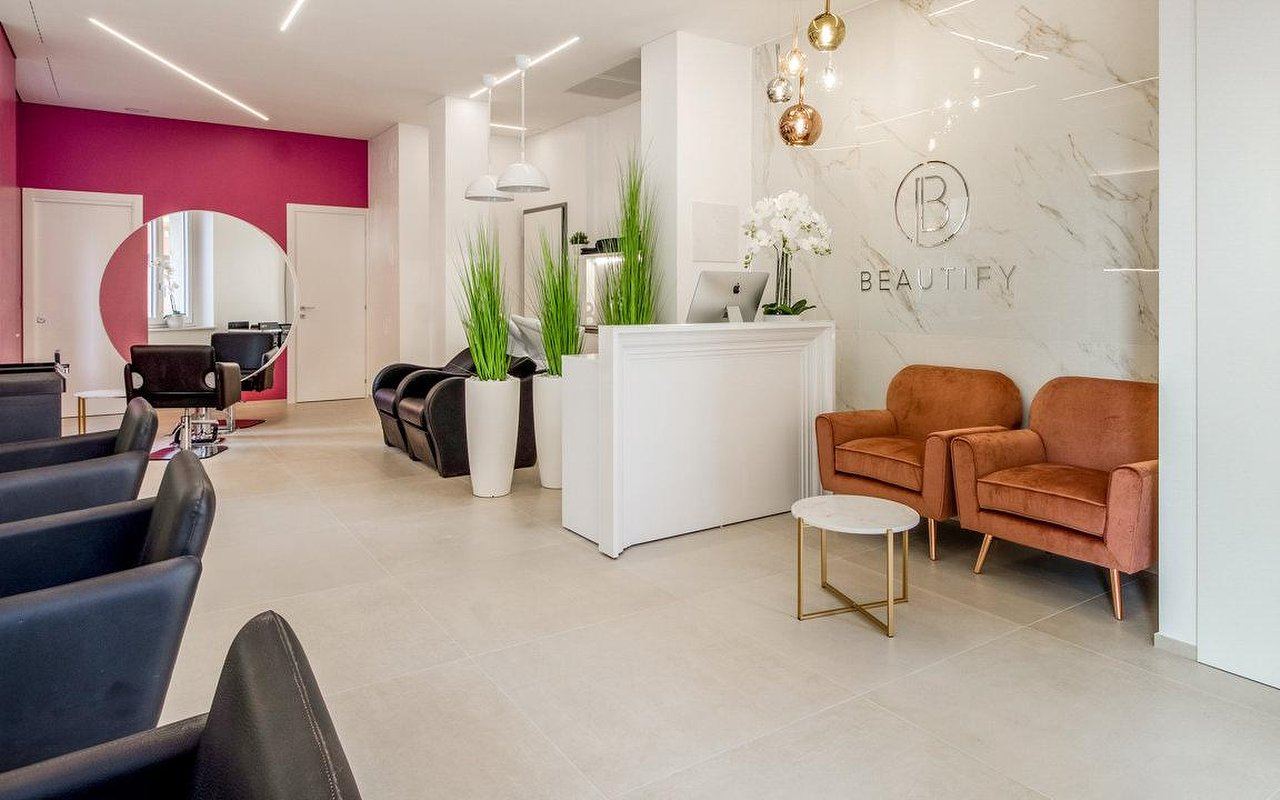 Vista del salone con reception, poltrone color ruggine e specchio tondo